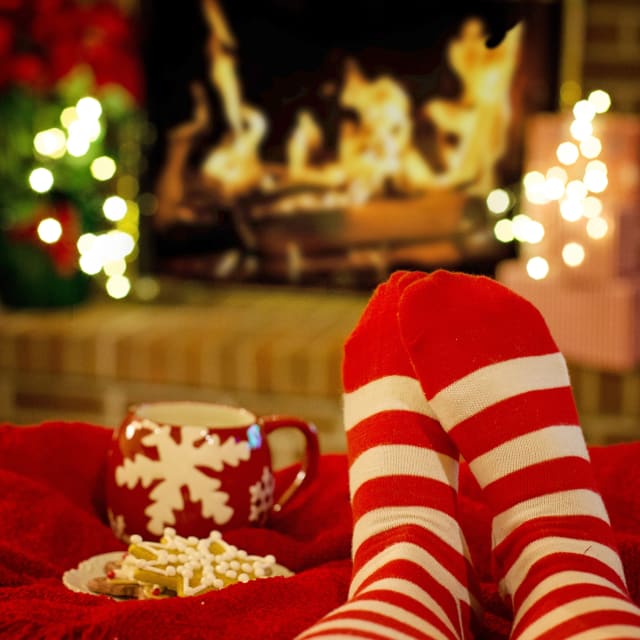 Feet wearing Christmas socks warming in front of a fire