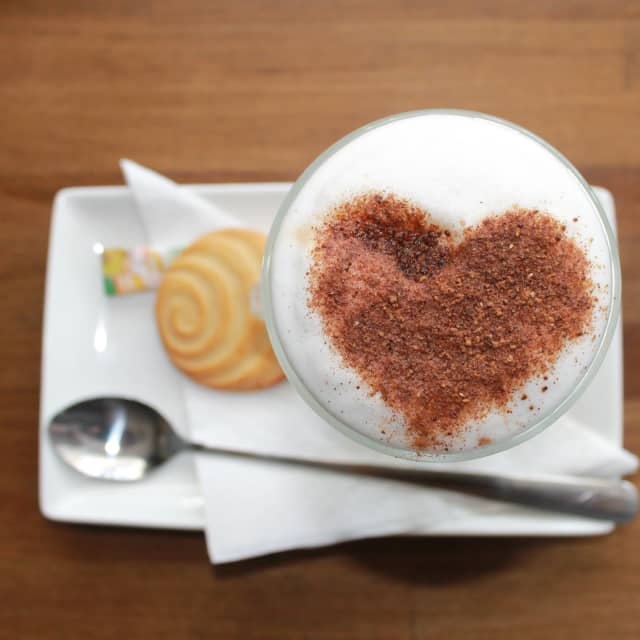 Coffee with foam and heart shaped cocoa powder