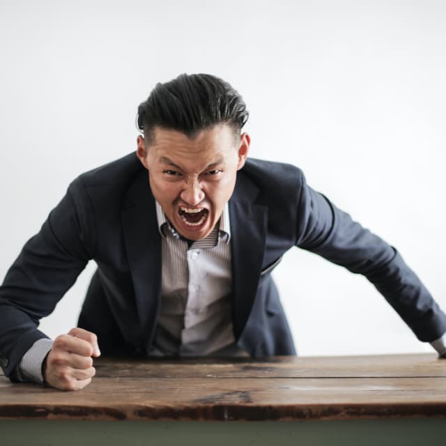 Man pounding a desk and yelling