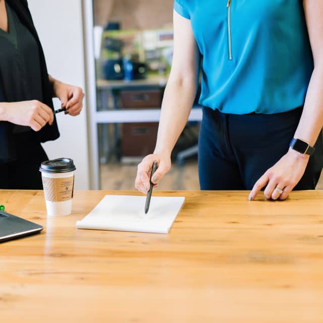 Two women reviewing notes at a desk