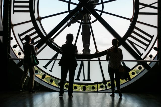 Three people inside a clock tower looking at the clock face