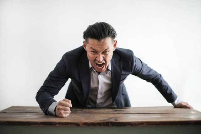 Man pounding a desk and yelling
