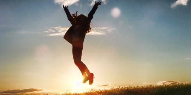 Woman jumping and rejoicing at sunset